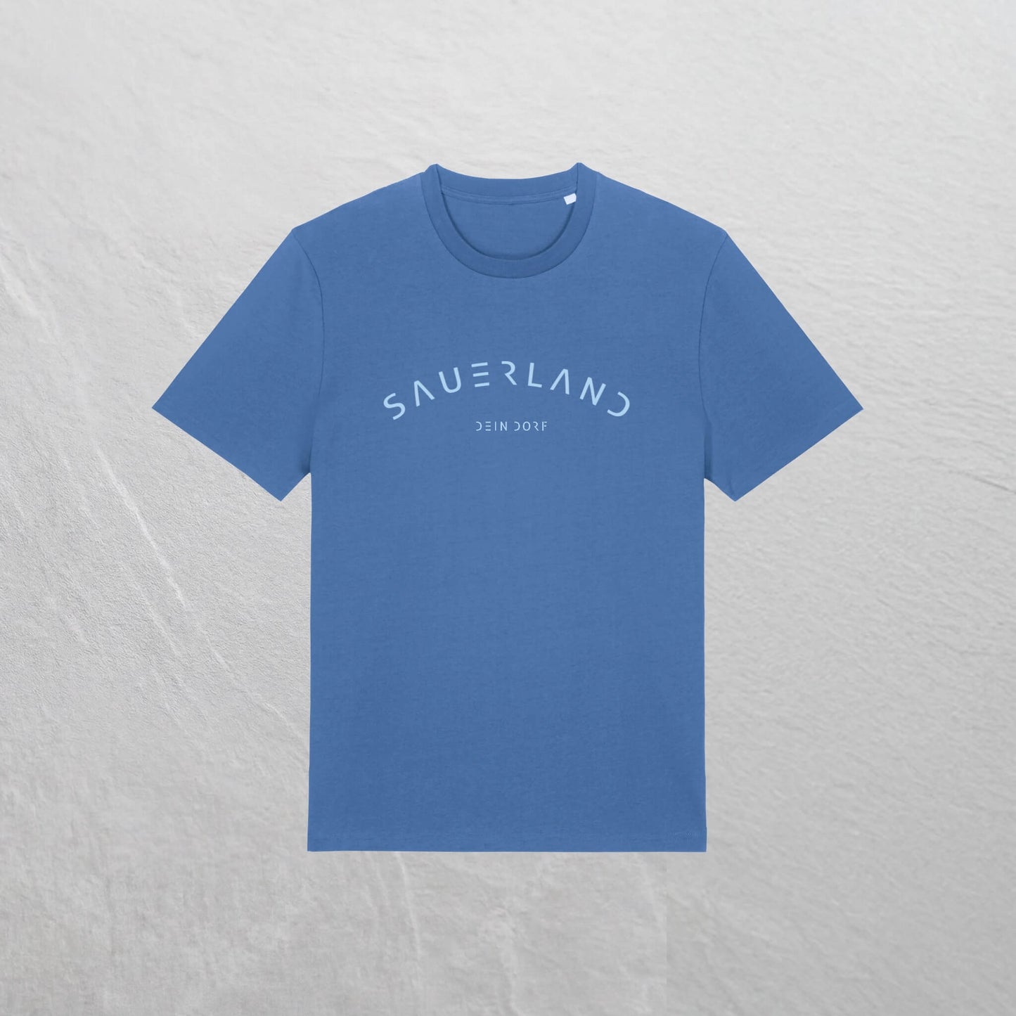 Mittelblaues T-Shirt mit leicht gerundetem Sauerland-Schriftzug liegt auf einem Holzhintergrund. In der Mitte unter dem Sauerland-Schriftzug ist der Dorfname Kierspe eingedruckt. Der Aufdruck ist hellblau.